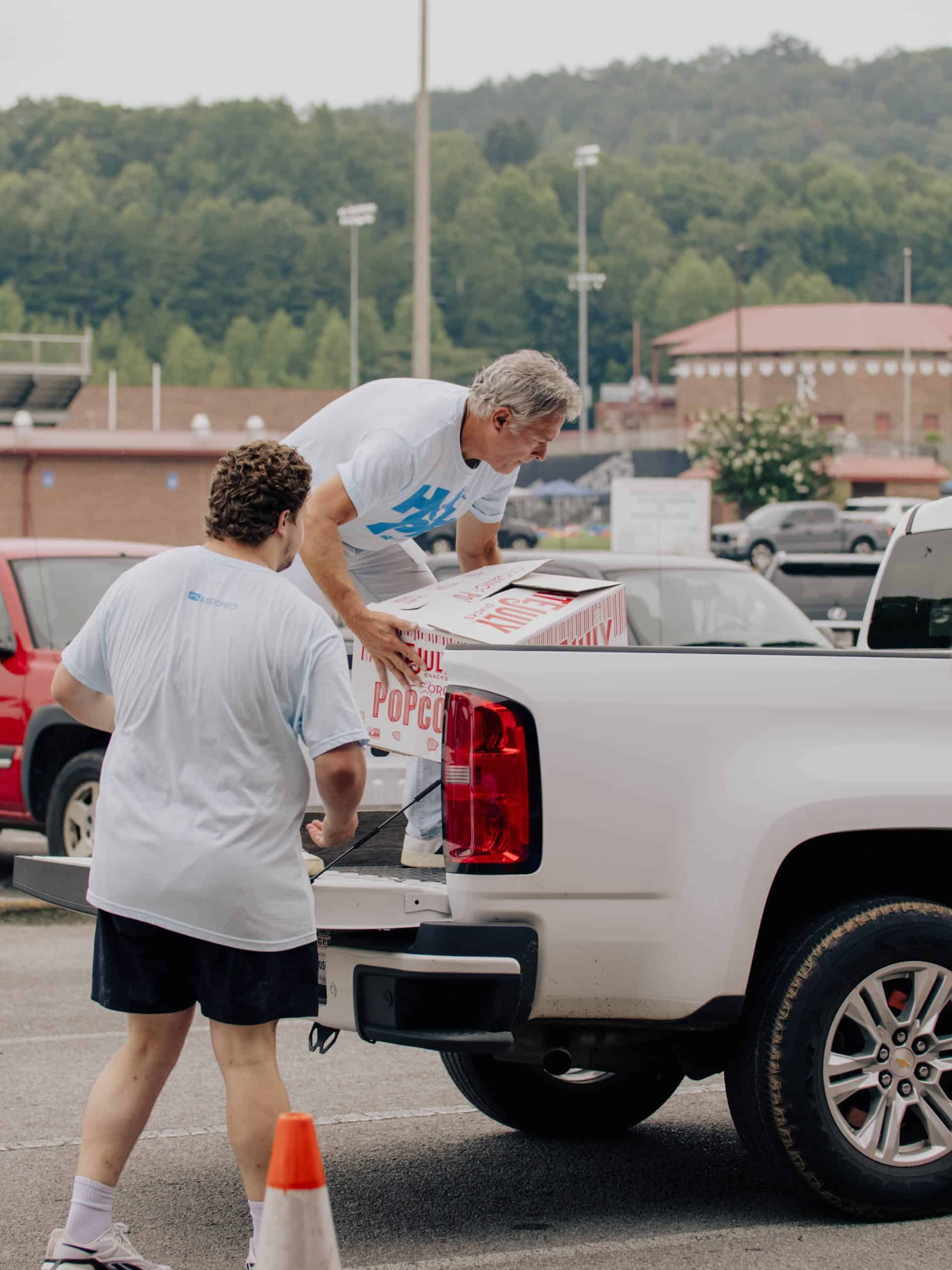 Two men loading a truck with food
